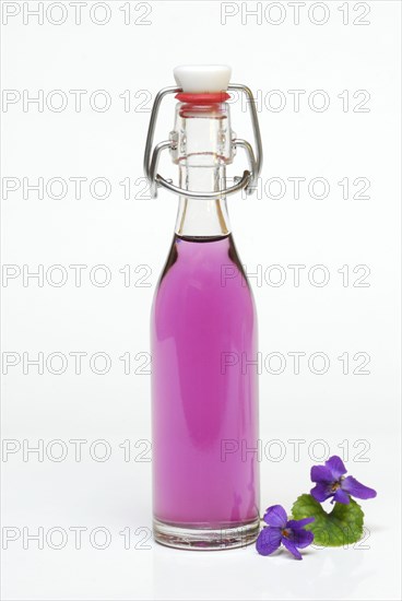 Violet syrup in bottle and violet flowers