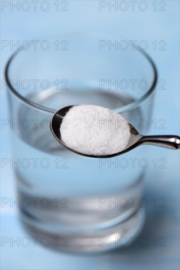 Spoon with baking soda and glass of water