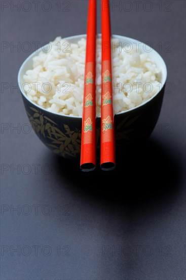 Boiled rice in bowl with chopsticks