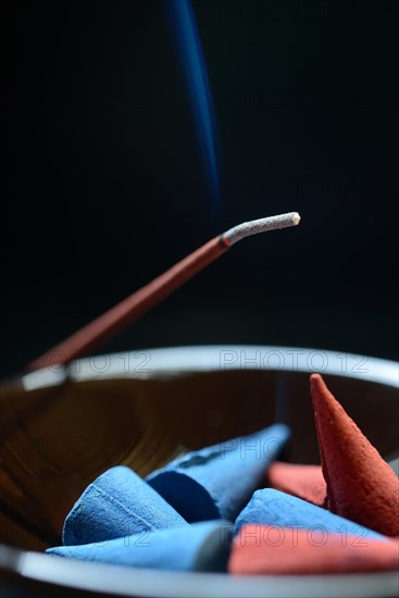 Incense cones in bowl and burning incense sticks