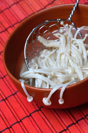 Boiled Golden needle mushroommushrooms in bowl with strainer