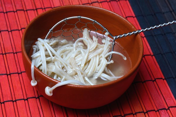 Boiled Golden needle mushroommushrooms in bowl with strainer