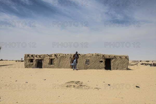 Man in front of traditional mud house
