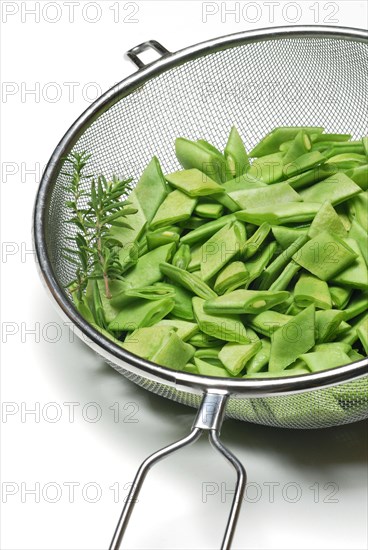 Sliced broad beans with savory in kitchen sieve