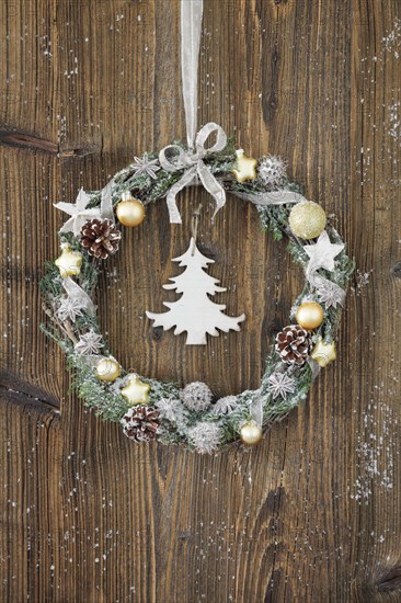 Christmas wreath on brown wooden wall with fir tree