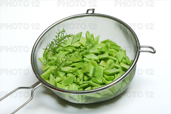 Sliced broad beans with savory in kitchen sieve
