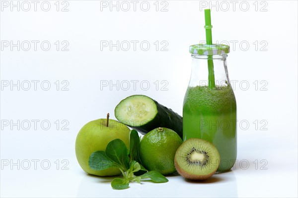 Green smoothie in glass with straw and fruit and vegetables