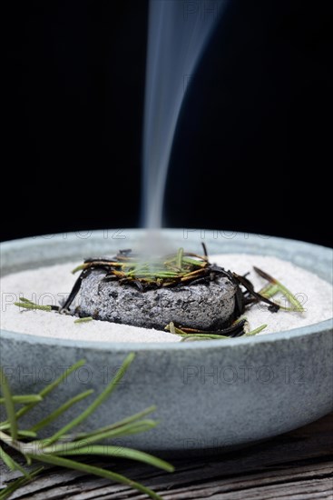 Dried rosemary leaves are burnt in a bowl with sand