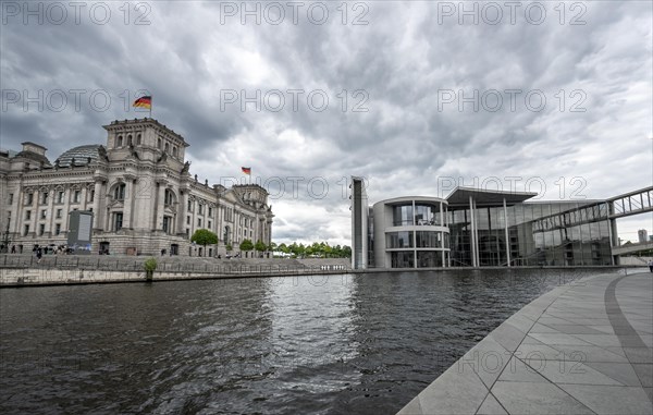 Reichstag building with waving German flag and Paul Loebe House on the Spree