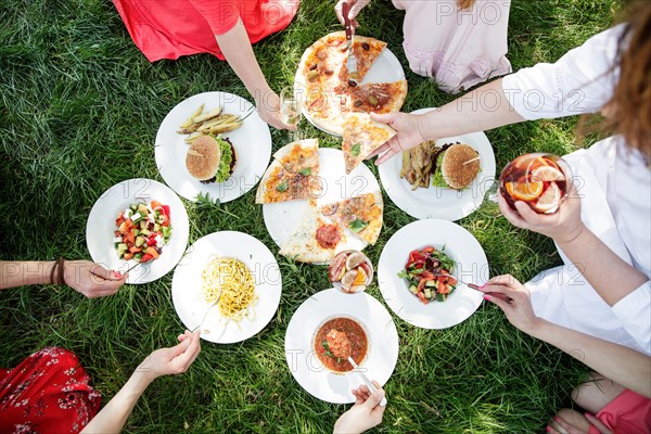 Group of women enjoying different food on grass