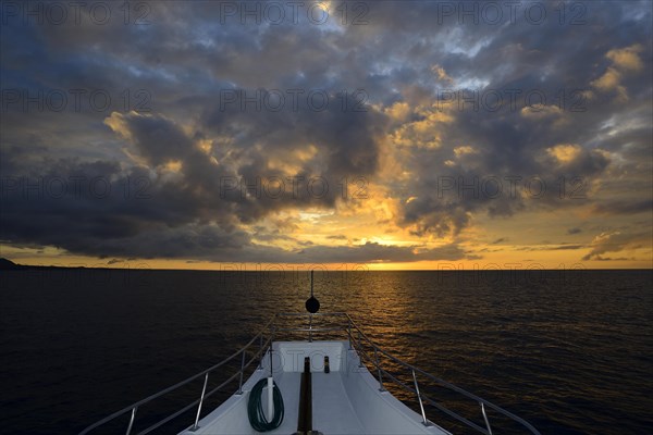 Bow of a ship in sunset with clouds over the Pacific Ocean