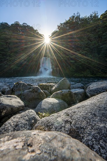 Waterfall in forest with sunbeams