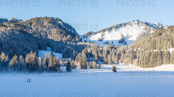 Frozen Spitzingsee in winter with walkers