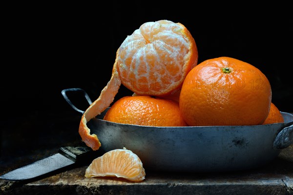 Unpeeled and half-peeled clementines in pan