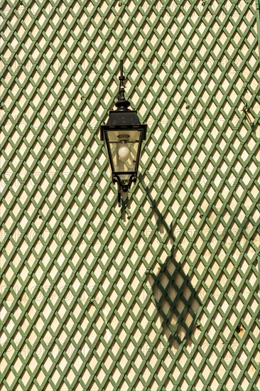 Shadow of a lantern on a green wooden lattice wall