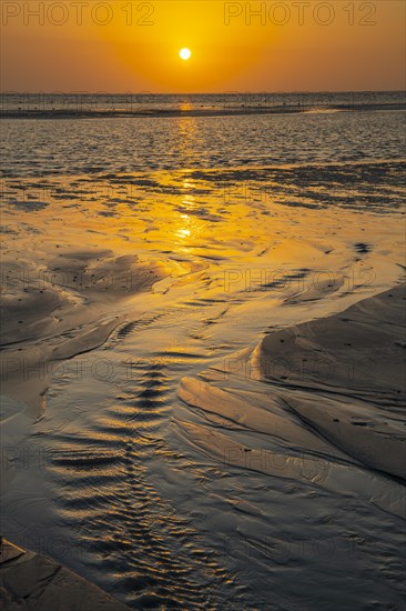 Sunset over tidal creek on sandy beach