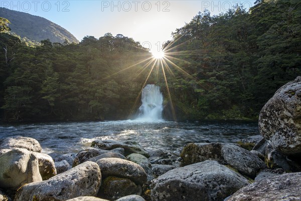 Waterfall in forest with sunbeams