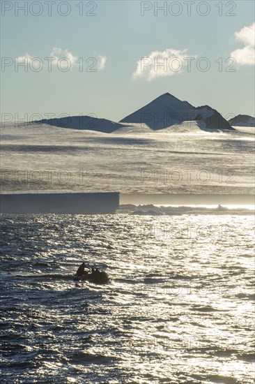 Backlight of a Zodiac with tourists cruising through the icebergs