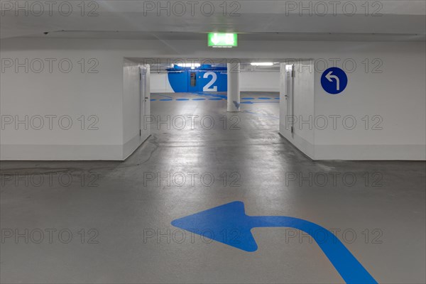 Empty underground car park and blue arrow on the floor