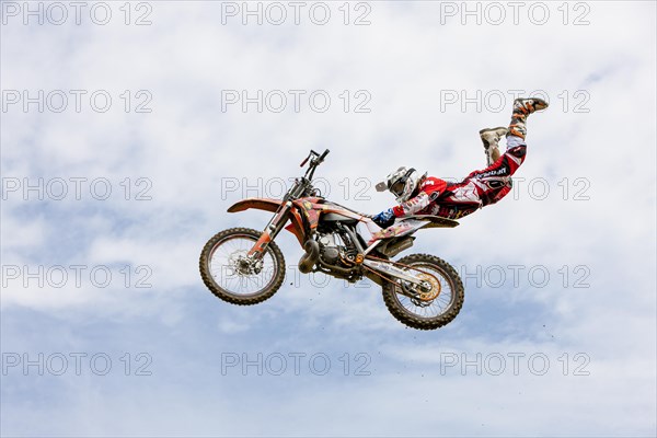 Motocross rider jumping in front of cloudy sky