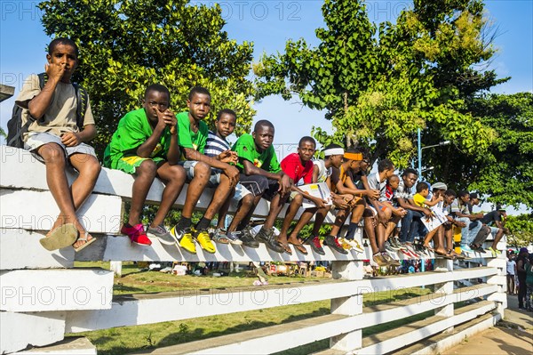 Boys on a wall watching the Carneval parade in the town of Sao Tome