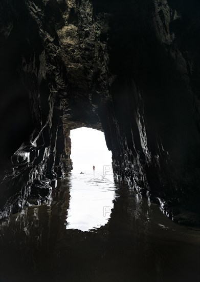 Silhouette of a person in front of cave exit in backlight