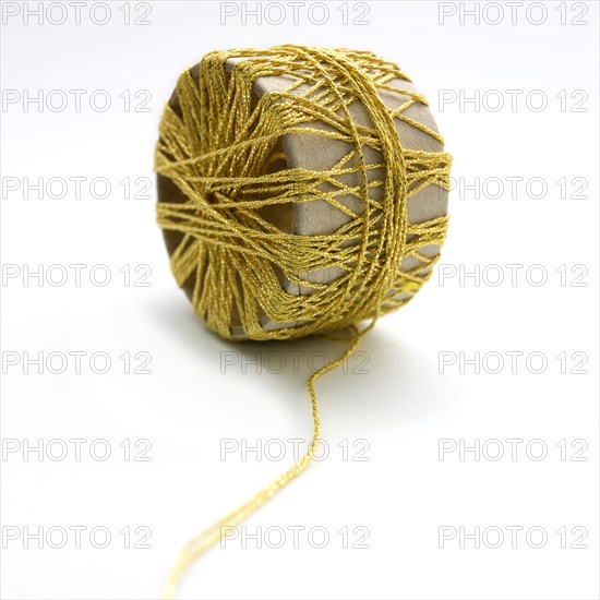 Bobbin of golden thread on white background