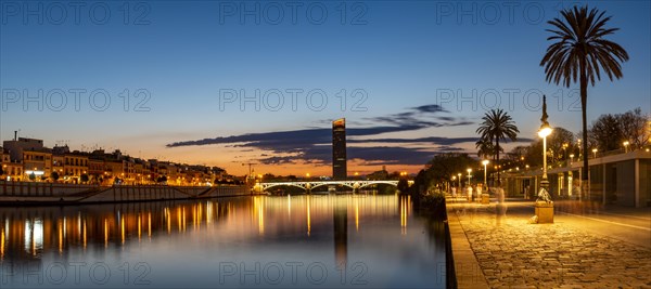 View over the river Rio Guadalquivir with illuminated bridge Puente de Triana and promenade