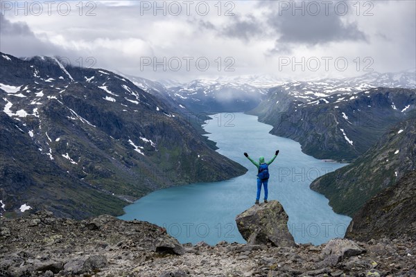 Hiker stands on rocks and stretches arms in the air