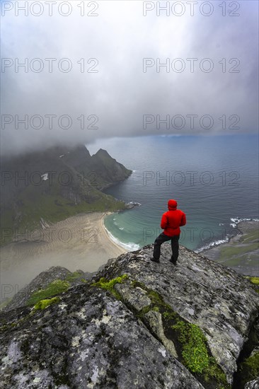 Hiker enjoys the view from Helvetestinden to the beach of Bunes