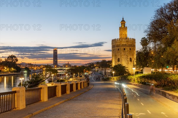 Boardwalk at the river Rio Guadalquivir with illuminated Torre del Oro