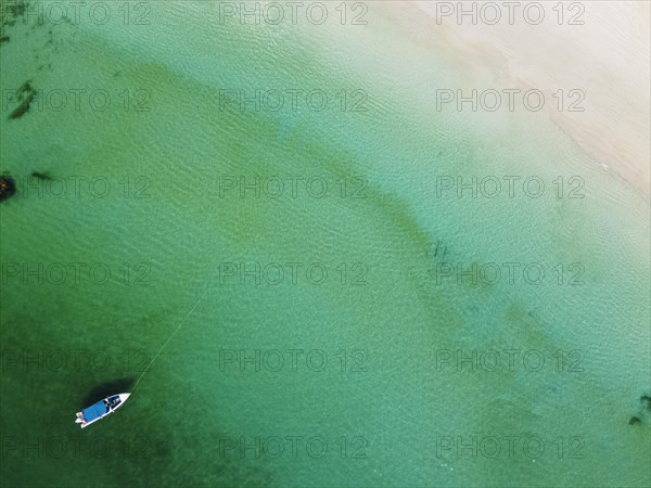 Aerial of a little boat in the clear waters anchoring on a beach on Smart island