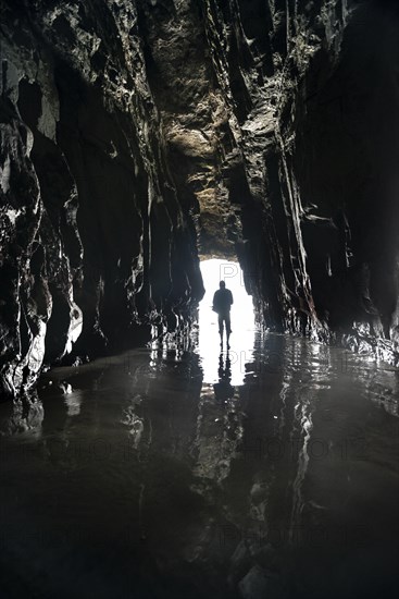 Silhouette of a person in front of cave exit in backlight