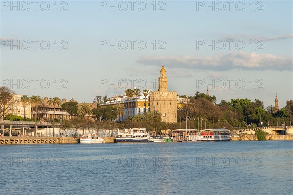 View over the river Rio Guadalquivir on promenade with excursion boats and Torre del Oro