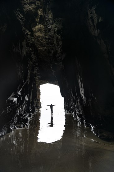 Silhouette of a person in front of cave exit in backlight