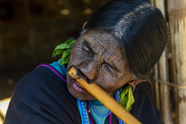 Chin woman with spiderweb tattoo blowing a flute with her nose