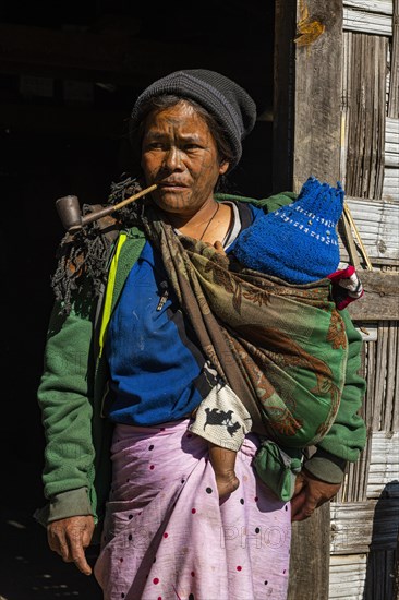 Chin woman with spiderweb tattoo smoking a pipe