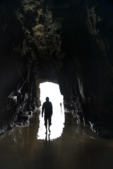 Silhouette of a person in front of cave exit in backlight