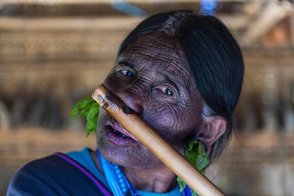 Chin woman with spiderweb tattoo blowing a flute with her nose