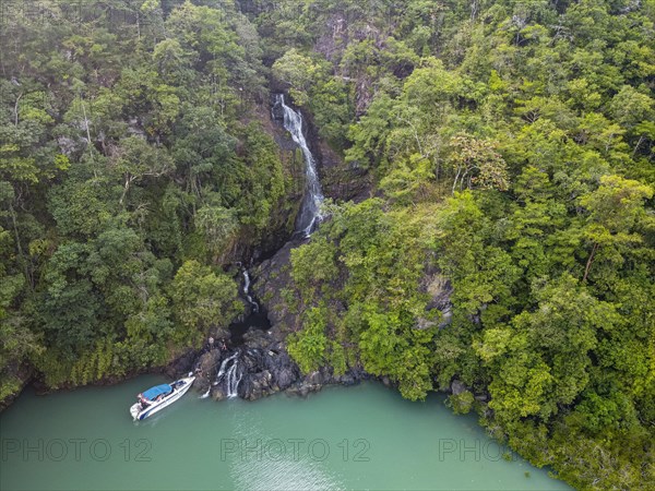 Aerial of a waterfall dropping right in the ocean on Dome island