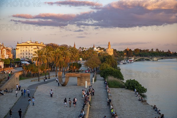 Waterfront promenade Muelle de la sal at the river Rio Guadalquivir with Monumento a la Tolerancia and Torre del Oro