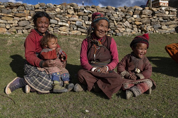 Women and children sitting in the evening sun in a meadow