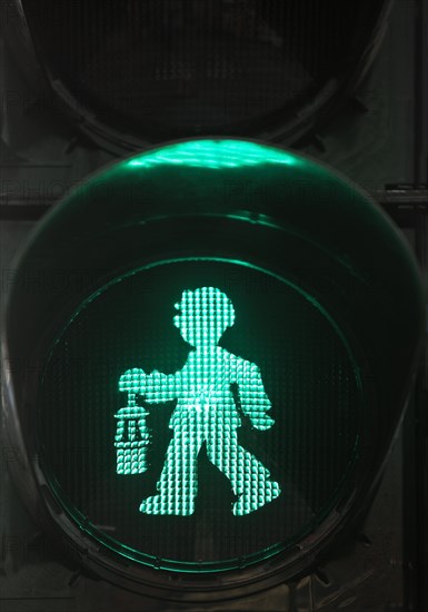 Green pedestrian traffic light man as miner with pit lamp