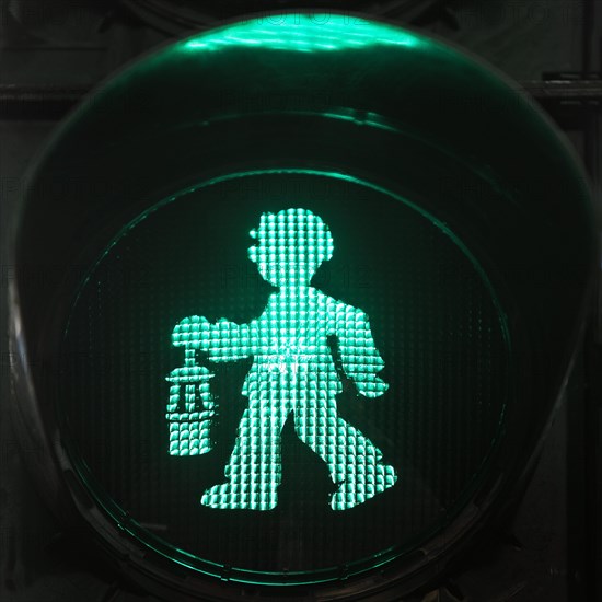 Green pedestrian traffic light man as miner with pit lamp