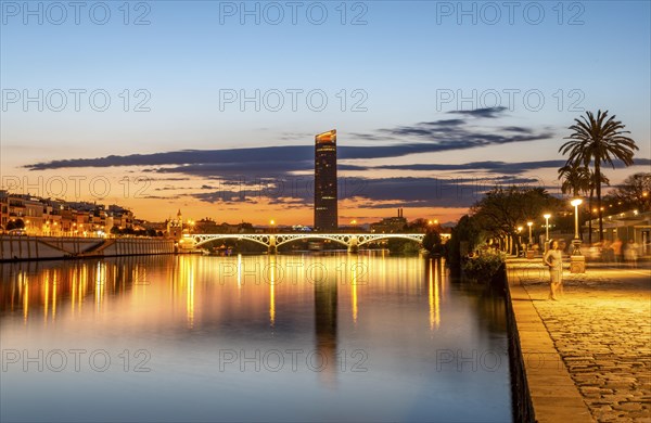 View over the river Rio Guadalquivir with illuminated bridge Puente de Triana and promenade