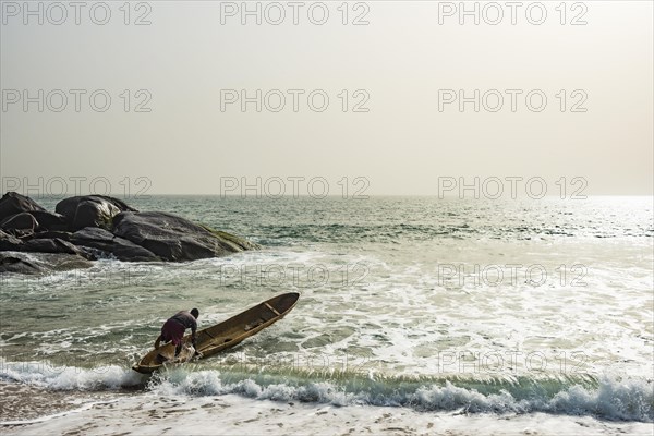 Man mounts his dugout canoe on the ocean east of Buchanan