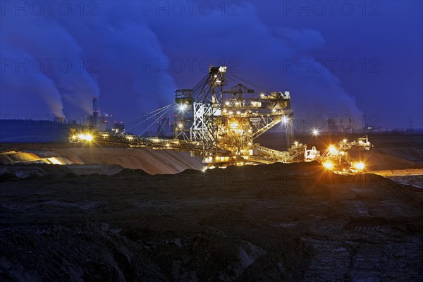 Opencast lignite mine with stacker and power plants in the evening
