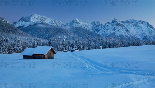 Winterly hummock meadows with hay barn and Karwendel mountains at dusk