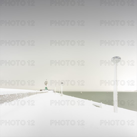Iced quay wall and lighthouse in the harbour of Sassnitz on the island of Ruegen