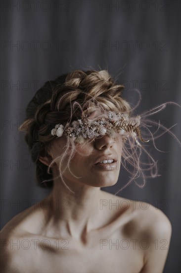 Young woman with wreath of flowers in front of eyes